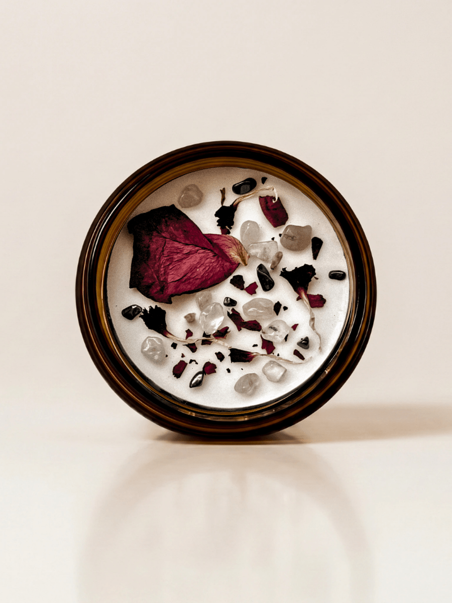 Ethereal ritual candle with rose quartz, hematite, quartz, and botanical details viewed from above.
