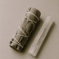 Rolled sage bundle and selenite wand on a beige background.