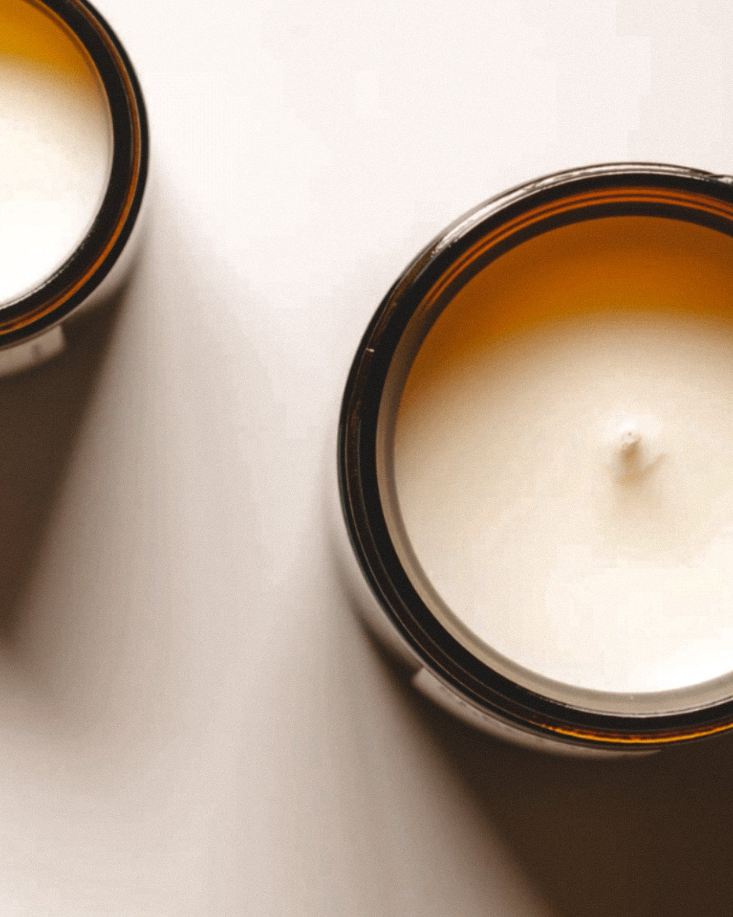 Two coconut apricot wax candles in glass containers on a light surface.