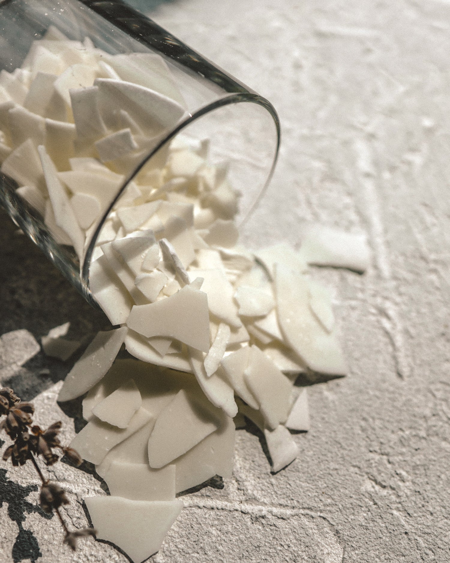 Glass container filled with coconut apricot wax on a textured surface.