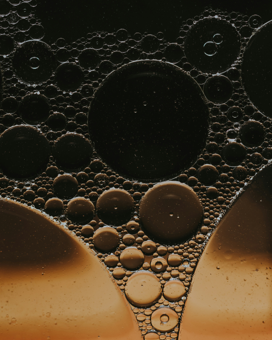 Close-up of brown bubbles of fragrance oil on a dark background.