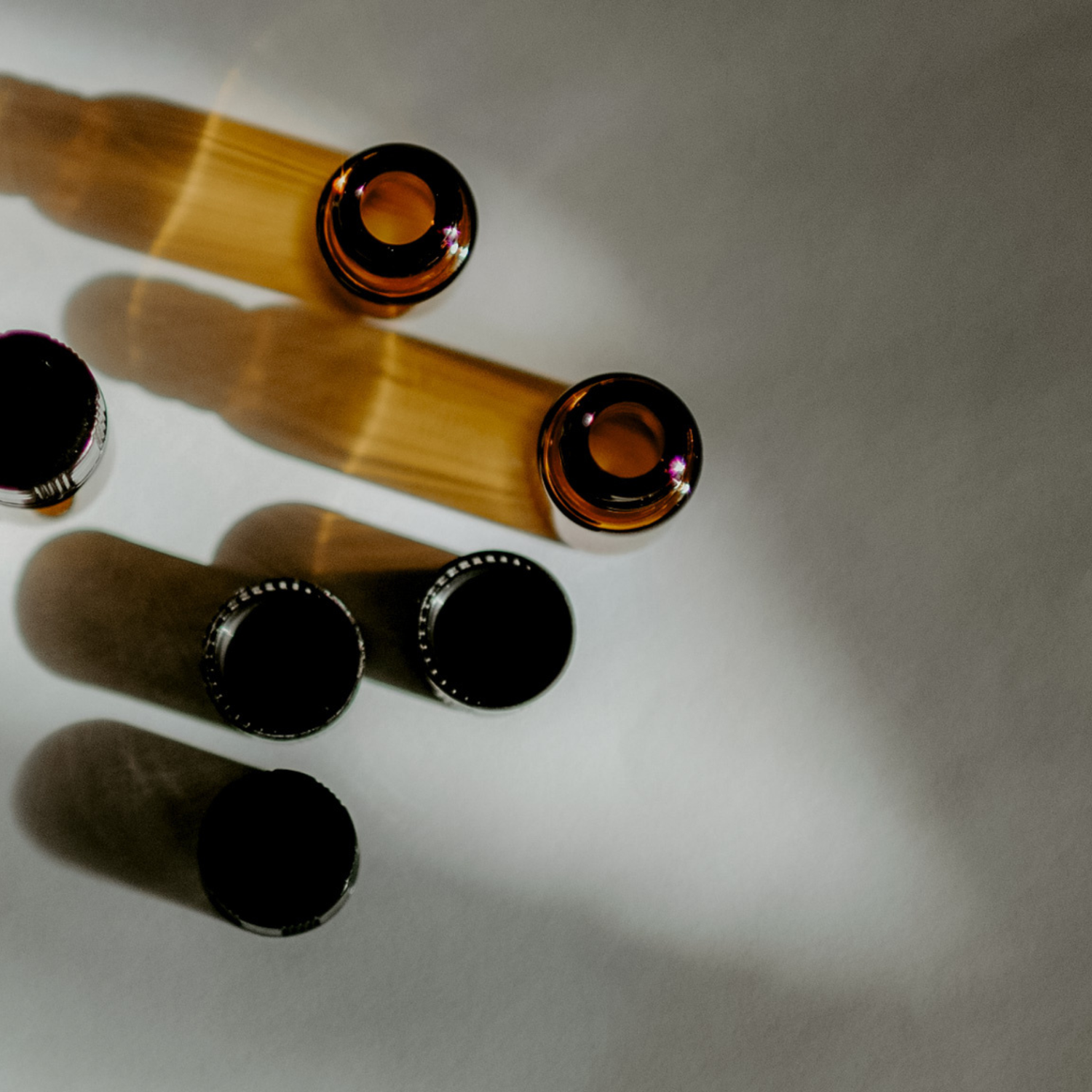Amber glass bottles with black caps on a white surface.