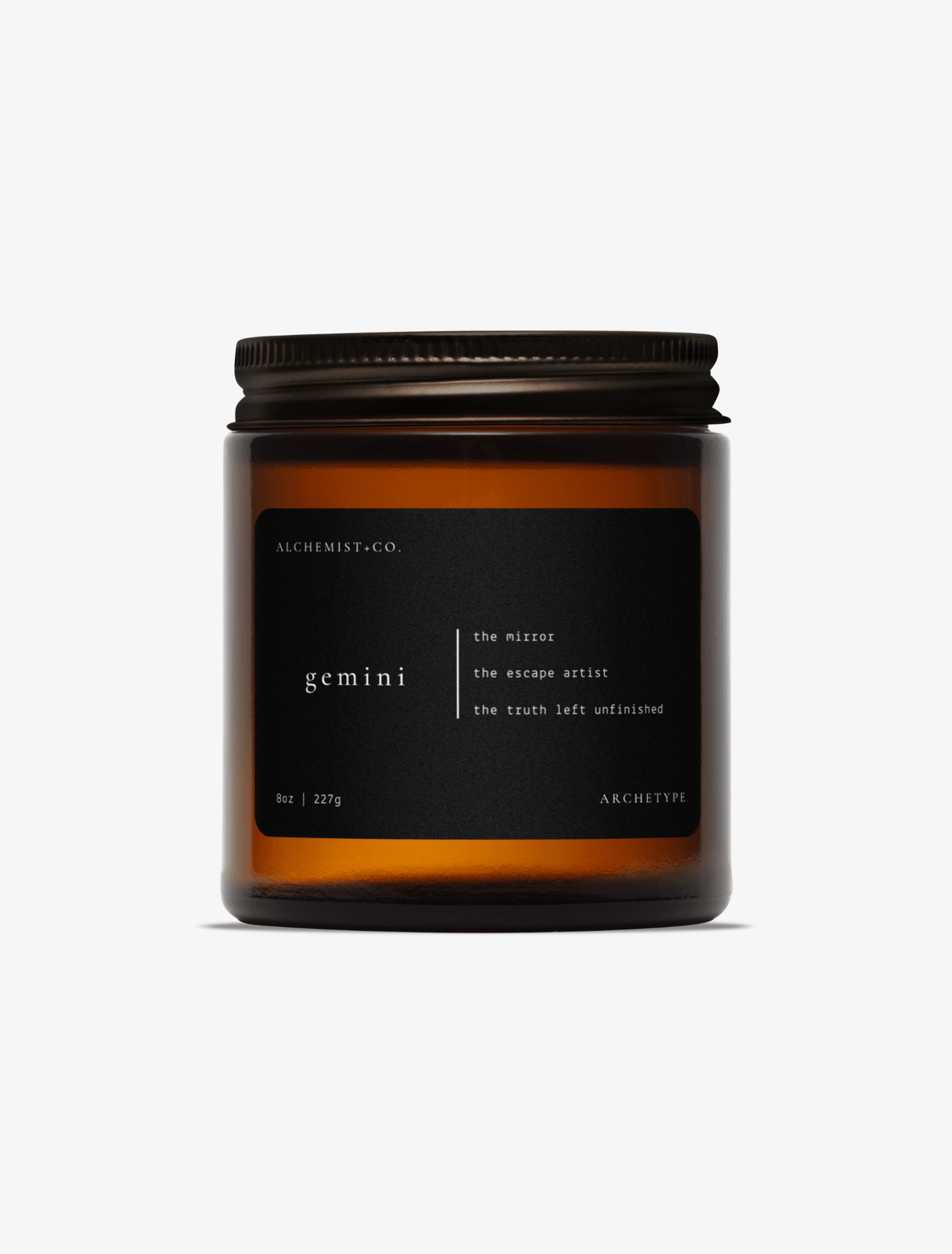 Gemini scented candle by Alchemist + Co. in an amber glass jar with a black label