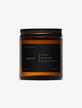 Gemini scented candle by Alchemist + Co. in an amber glass jar with a black label