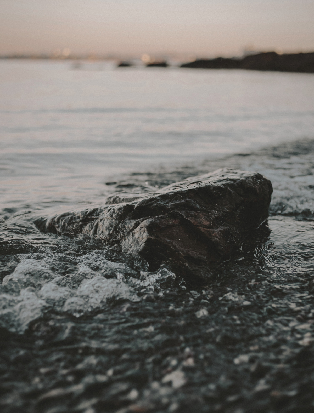 A dark, wet stone at the shoreline as water moves around it, the hero note of the Gravity candle