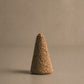 Close up of a Palo Santo incense cone on a neutral background.