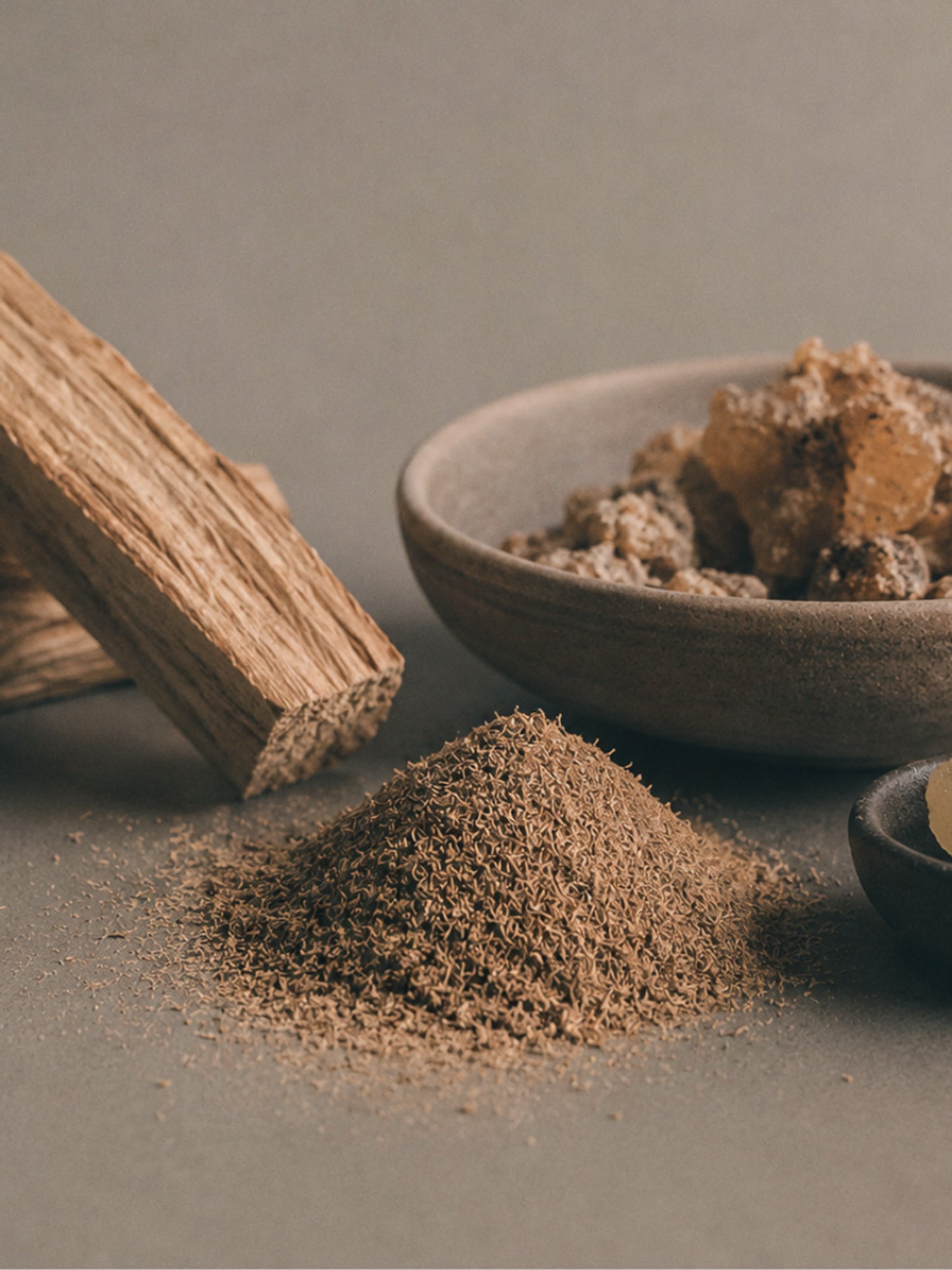Wooden tool, bowl with ground substance, and pile of ground material on a neutral background
