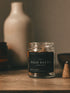 Jar of Palo Santo incense cones on a wooden surface with a blurred vase in the background.