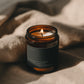 Hazelnut Coffee + Almond Cream Bare candle burning beside soft linen in warm atmospheric light.