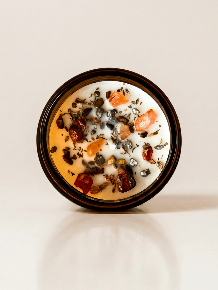 I. The Magician ritual candle with carnelian, pyrite, tiger's eye, and botanical details viewed from above.