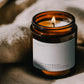 Lit III. The Empress ritual candle beside textured linen in warm atmospheric light.