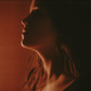 Leo woman with fiery red hair with a powerful expression against a red lit background.
