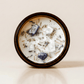 New Moon ritual candle with lapis lazuli, moonstone, quartz, and botanical details viewed from above.