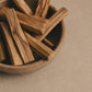 Wooden bowl of Palo Santo sticks on a neutral background.
