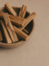 Wooden bowl of Palo Santo sticks on a neutral background.