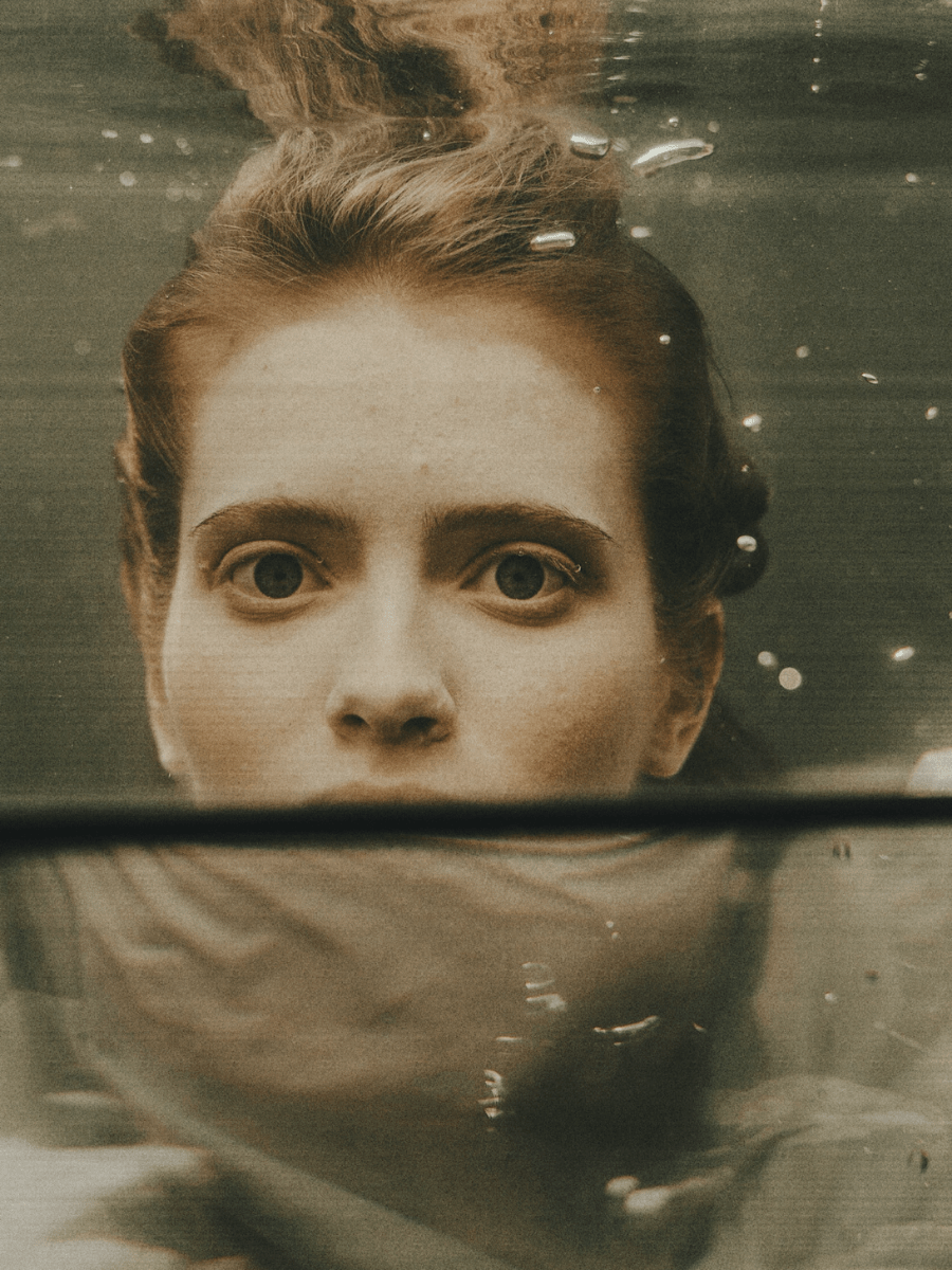 A Pisces woman underwater wide eyed and pensive.