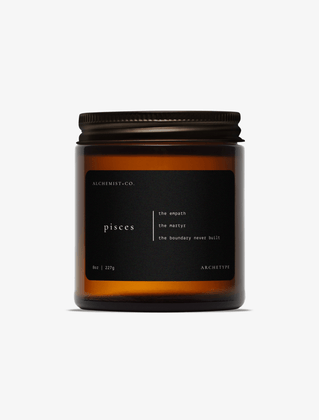 Pisces scented candle by Alchemist + Co. in an amber glass jar with a black label