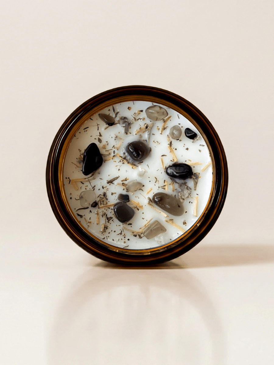 Protection ritual candle with black tourmaline, smoky quartz, obsidian, and botanical details viewed from above.