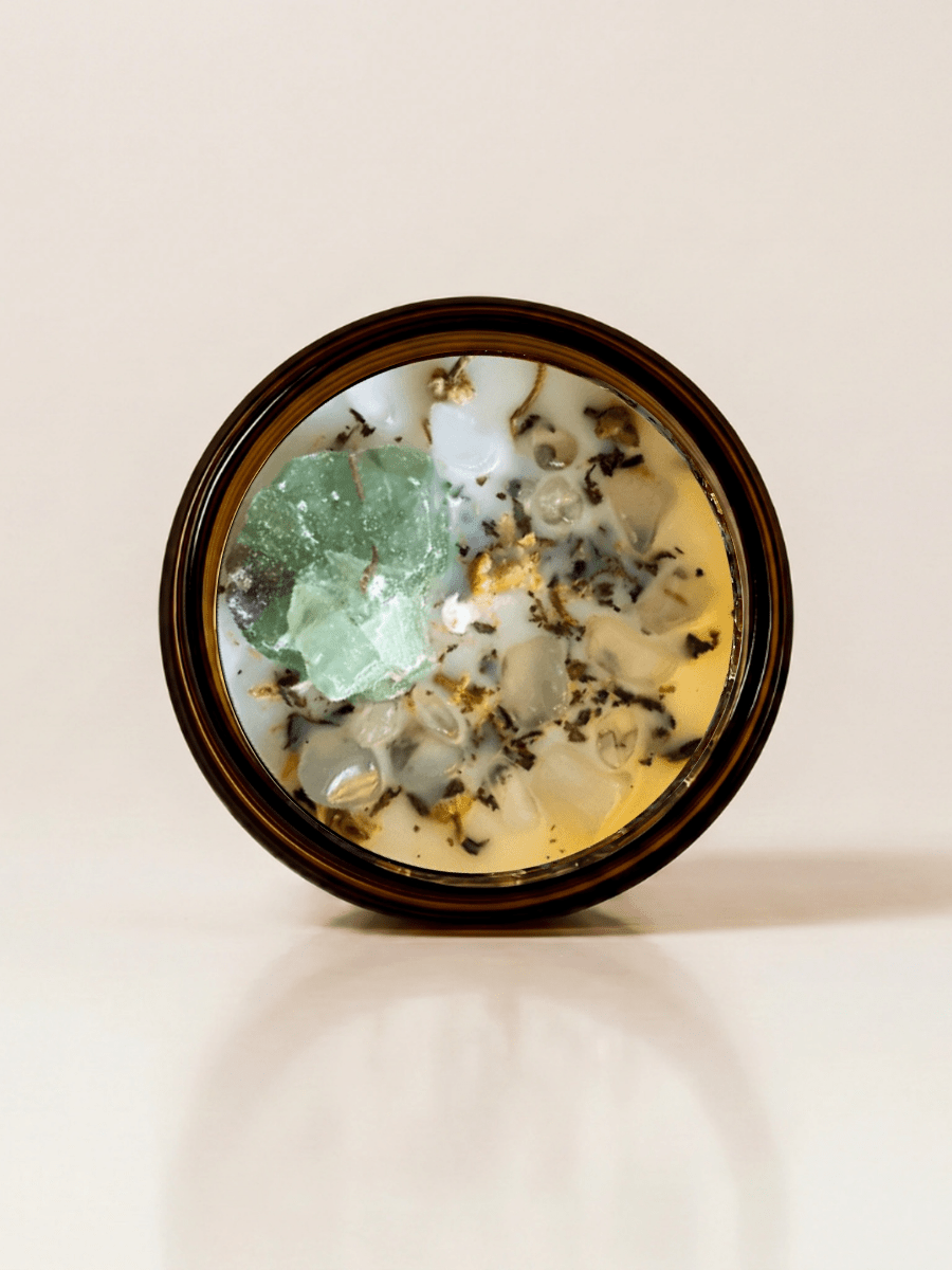 Release ritual candle with green calcite, quartz, and botanical details viewed from above.