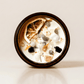 Renewal ritual candle with moonstone, black tourmaline, rutilated quartz, and botanical details viewed from above.