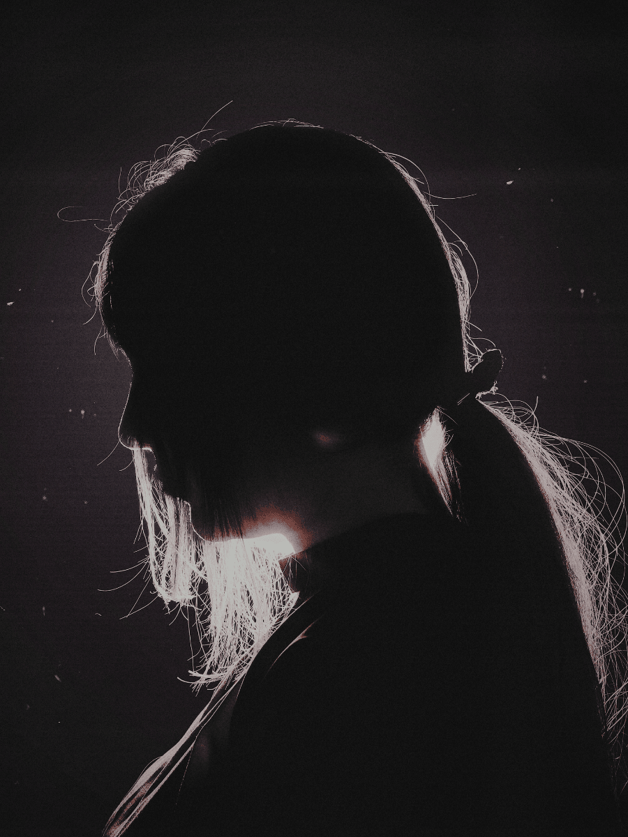 Scorpio woman side profile with soft light against dark shadows and background.