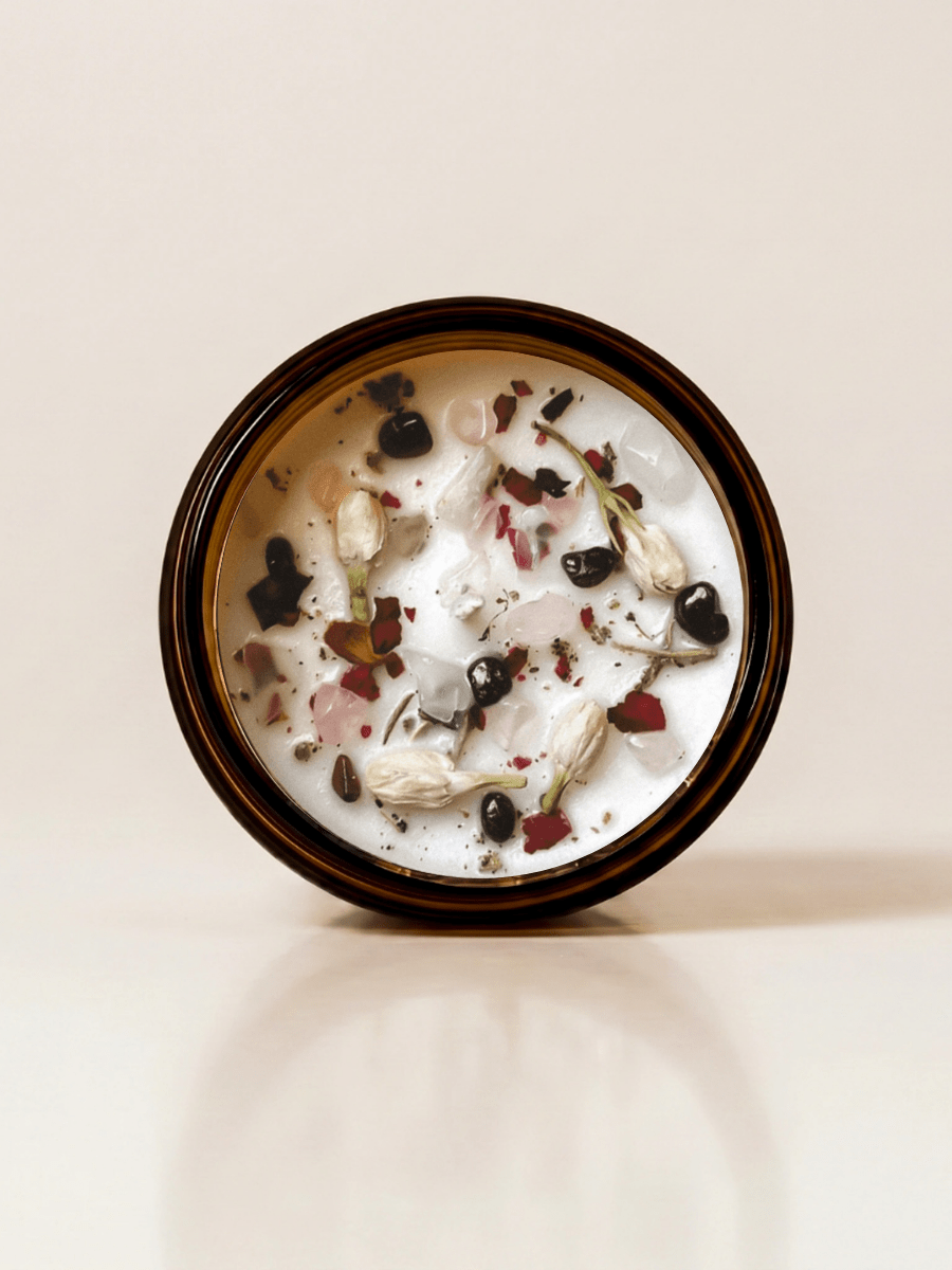 Self Love ritual candle with rose quartz, moonstone, garnet, and botanical details viewed from above.