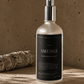 Bottle of 'Smudge' meditation mist on a wooden surface with a blurred background.