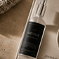 Smudge meditation mist bottle on a textured surface with a journal and sage.