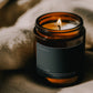 Lit Smudge ritual candle beside textured linen in warm atmospheric light.