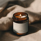 Sugared Lychee + Lotus Flower Bare candle burning beside soft linen in warm atmospheric light.