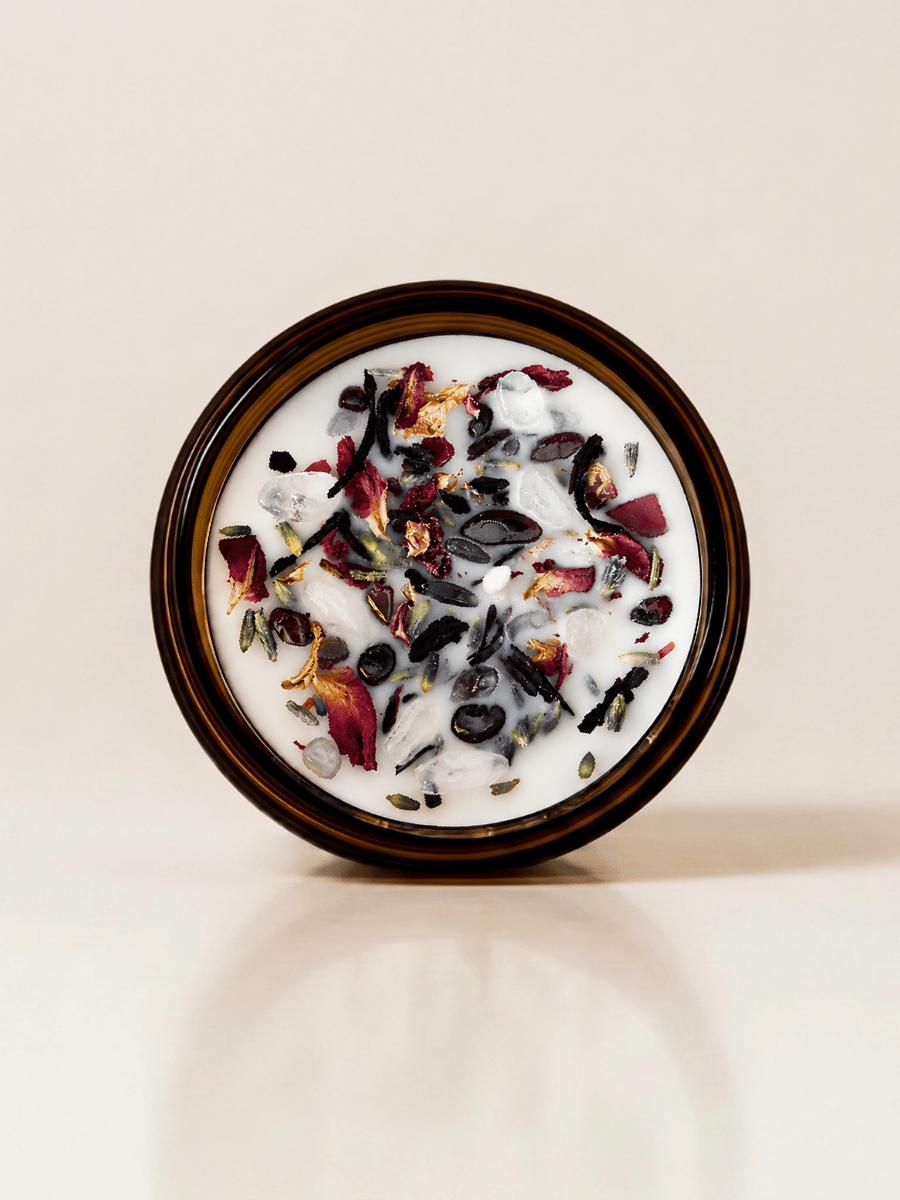 Tantra ritual candle with garnet, rose quartz, quartz, and botanical details viewed from above.