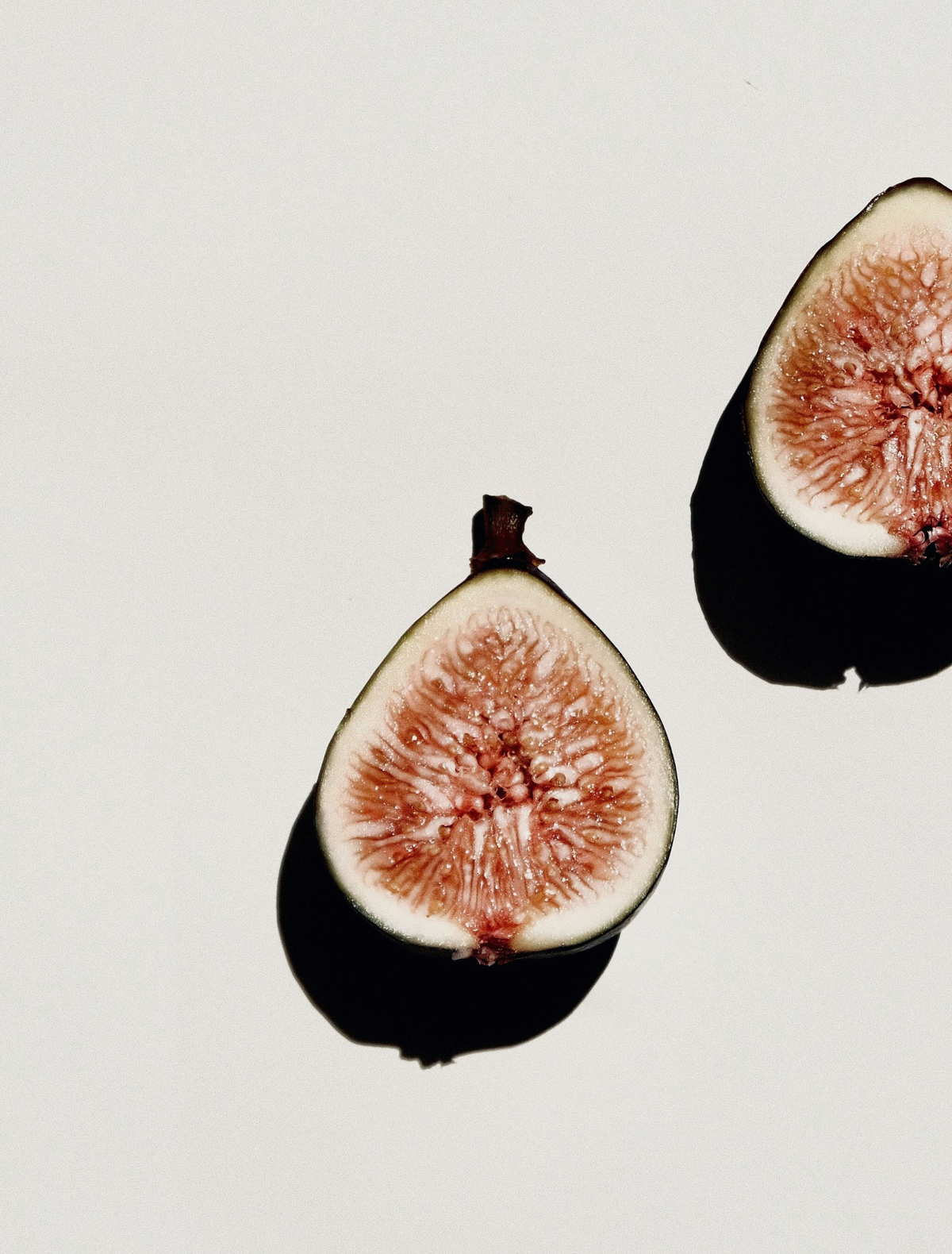 A halved fig with its deep interior in hard light, the hero note of the Throughline candle
