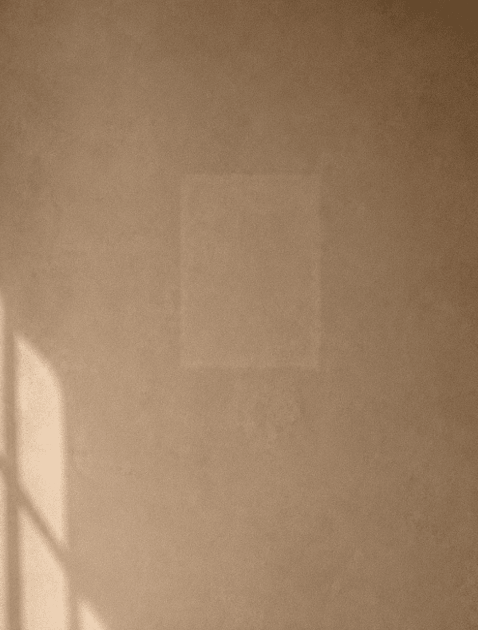 A warm beige textured surface with soft light shadowing on the left and a faint square outline in the center.