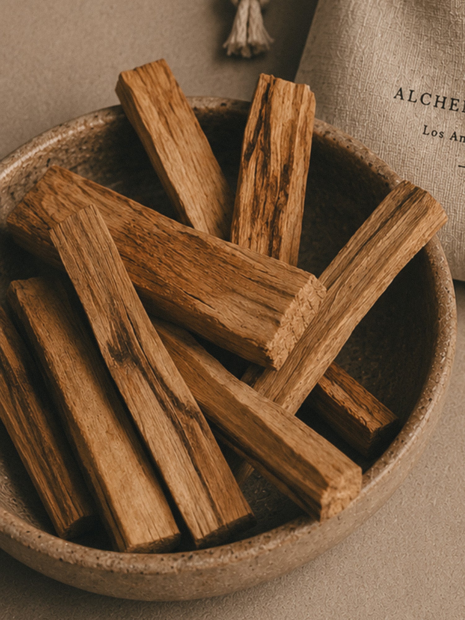 Ceramic bowl of Palo Santo sticks with a linen drawstring bag by Alchemist + Co.
