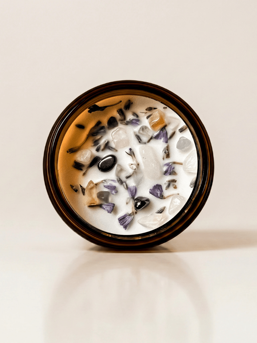 Yogi ritual candle with citrine, hematite, rose quartz, and botanical details viewed from above.